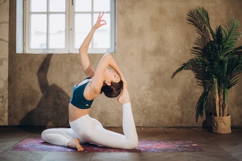 Woman in Blue Sports Bra and White Leggings Doing Yoga