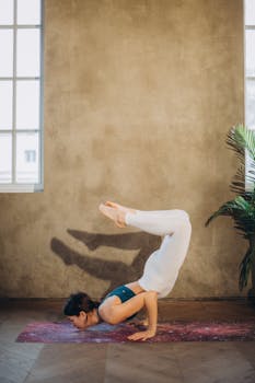 A woman performs a challenging scorpion yoga pose indoors, showcasing strength and balance.