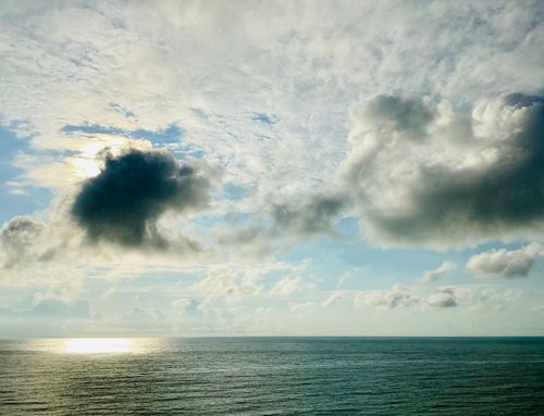 Free A captivating view of dramatic clouds over a calm ocean with sunlight piercing through. Stock Photo