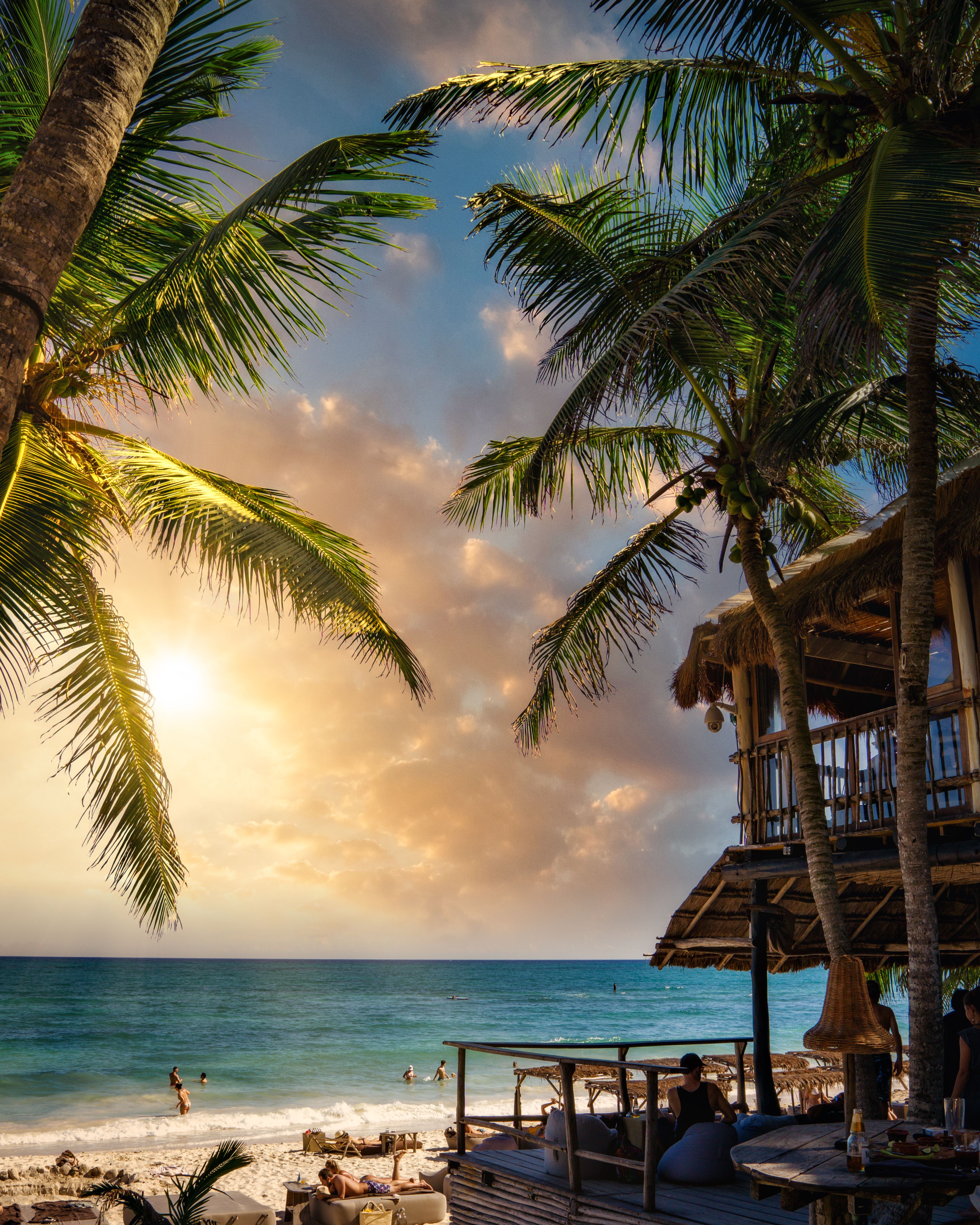 Sunset over a Tulum beach with coconut palms and calm sea in Mexico