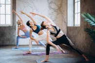 三名女性在明亮的室内工作室里练习瑜伽，展现出平衡性和灵活性