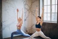 我在室内自然光线下，为两名表演瑜伽战士式的女性摆姿势