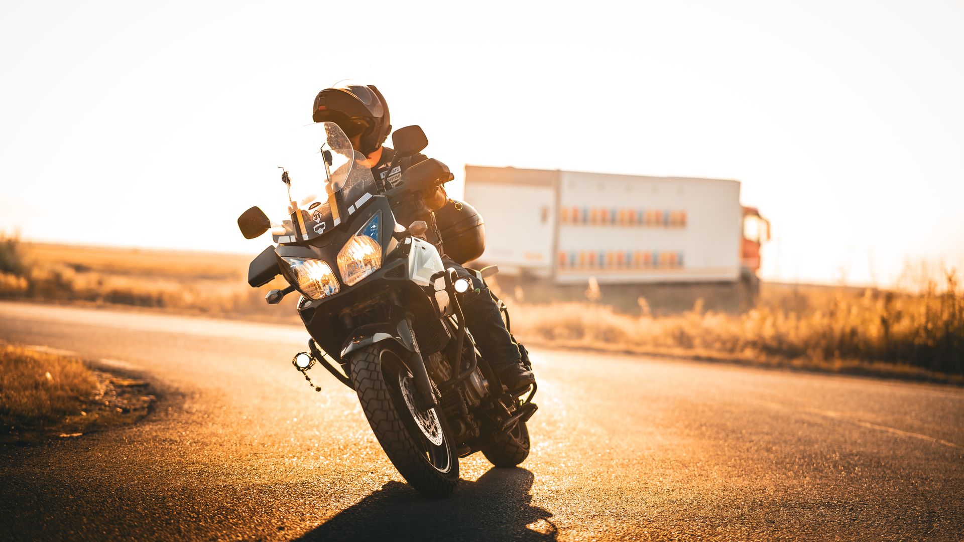 Modafinil for Truck Drivers: Enhancing Road Safety A motorcyclist rides with ease on a scenic road during a vibrant sunrise, passing a truck — modafinil for truck drivers