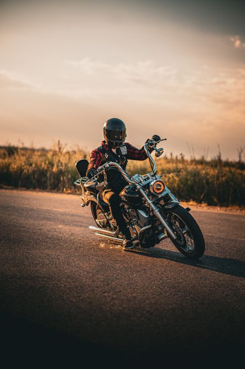 Free Rider on a motorcycle cruising on a rural road during a warm sunset. Stock Photo
