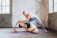 瑜伽老师帮助学生在室内做出头膝旋转姿势，促进灵活性和正念