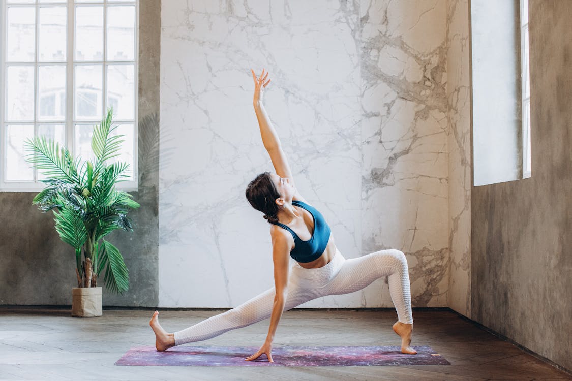 Woman in Blue Sports Bra and White Leggings Doing Yoga