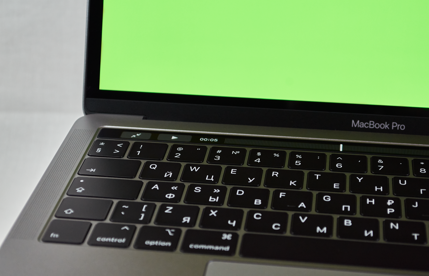 Russian keyboard MacBook Pro with a green screen. Modern electronic device.