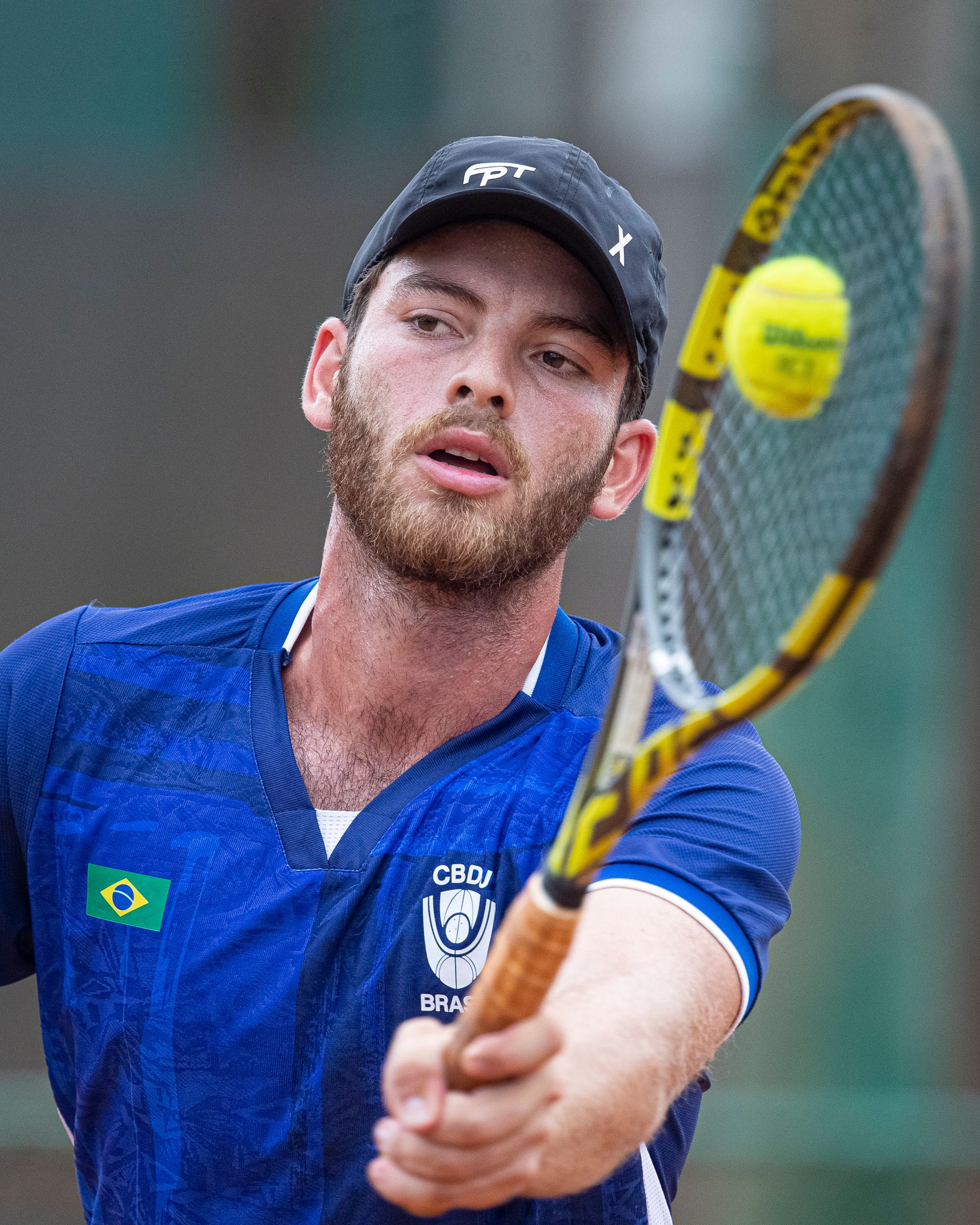 Close-up of a male tennis player focusing on returning a ball during a match.