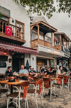 Outdoor scene at a cozy street cafe with people relaxing under Turkish flags in Bodrum, Turkey.