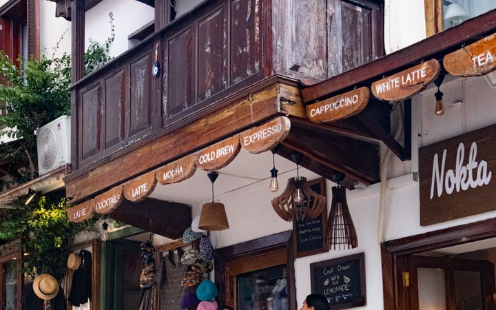 Two people enjoy coffee at an outdoor cafe in a charming town, with classic architecture and cozy ambiance.