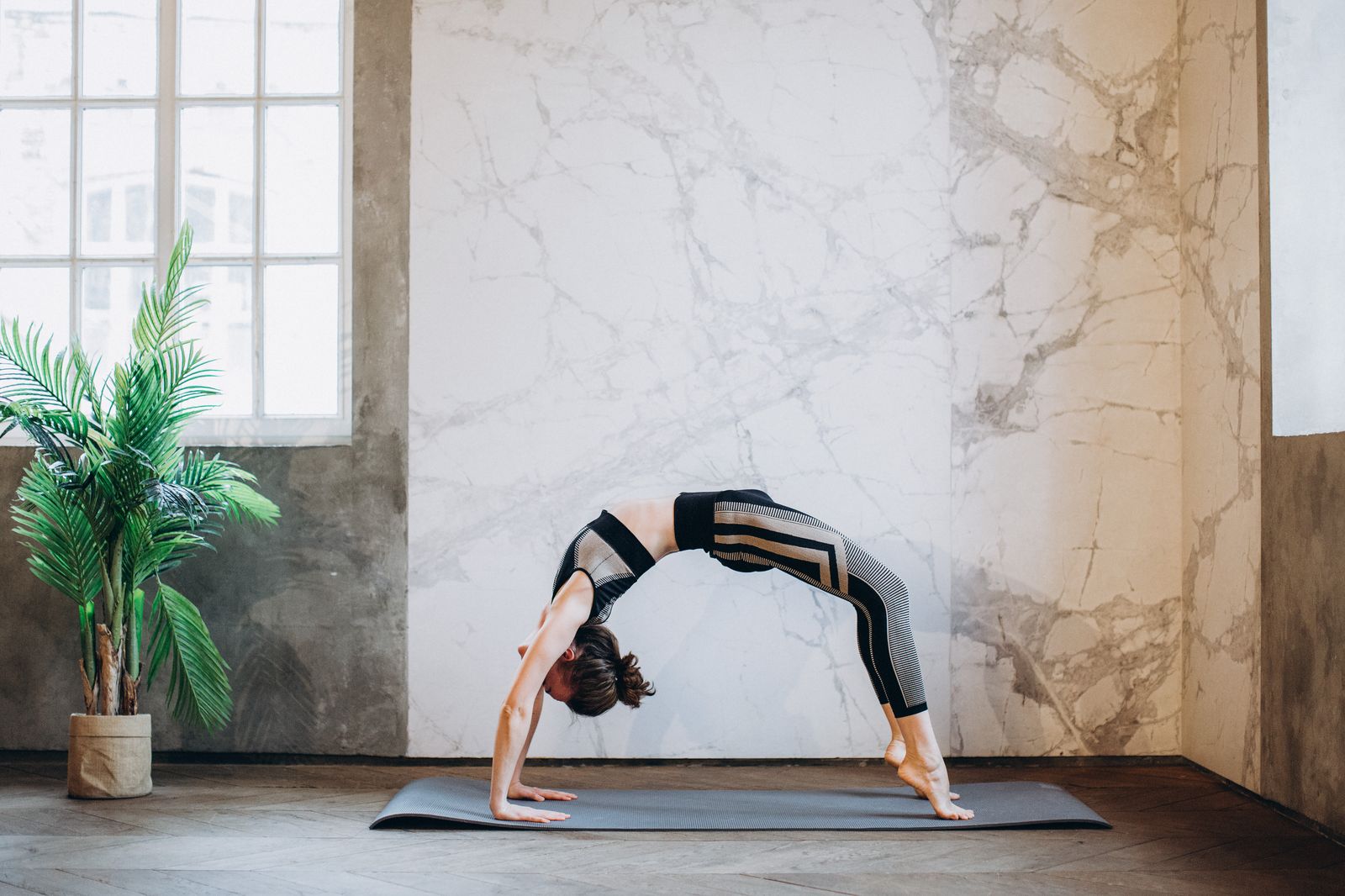 Adult woman practicing a yoga backbend pose in a calm indoor studio space