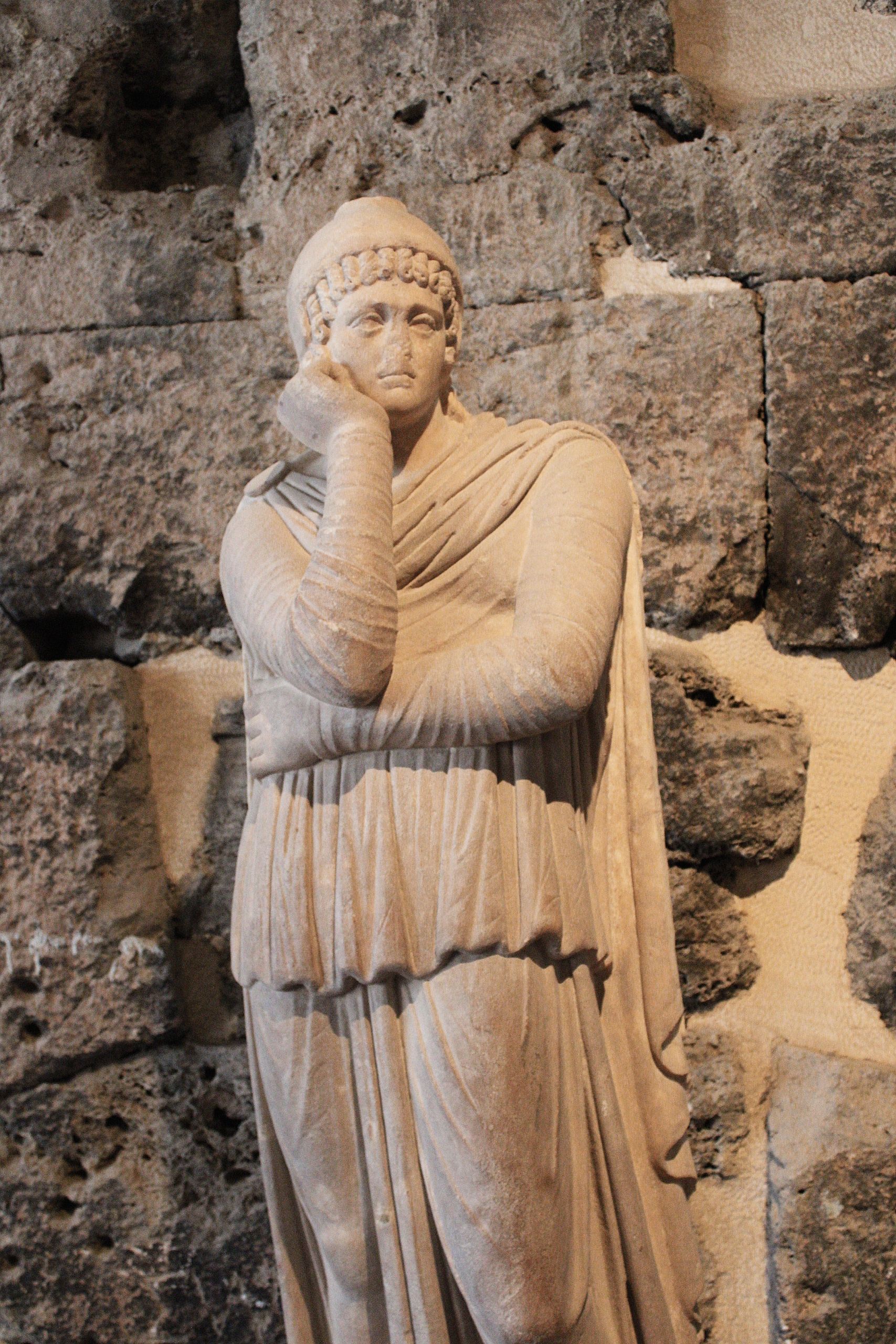 Ancient Roman statue in a historical stone setting, showcasing classical art and antiquity.