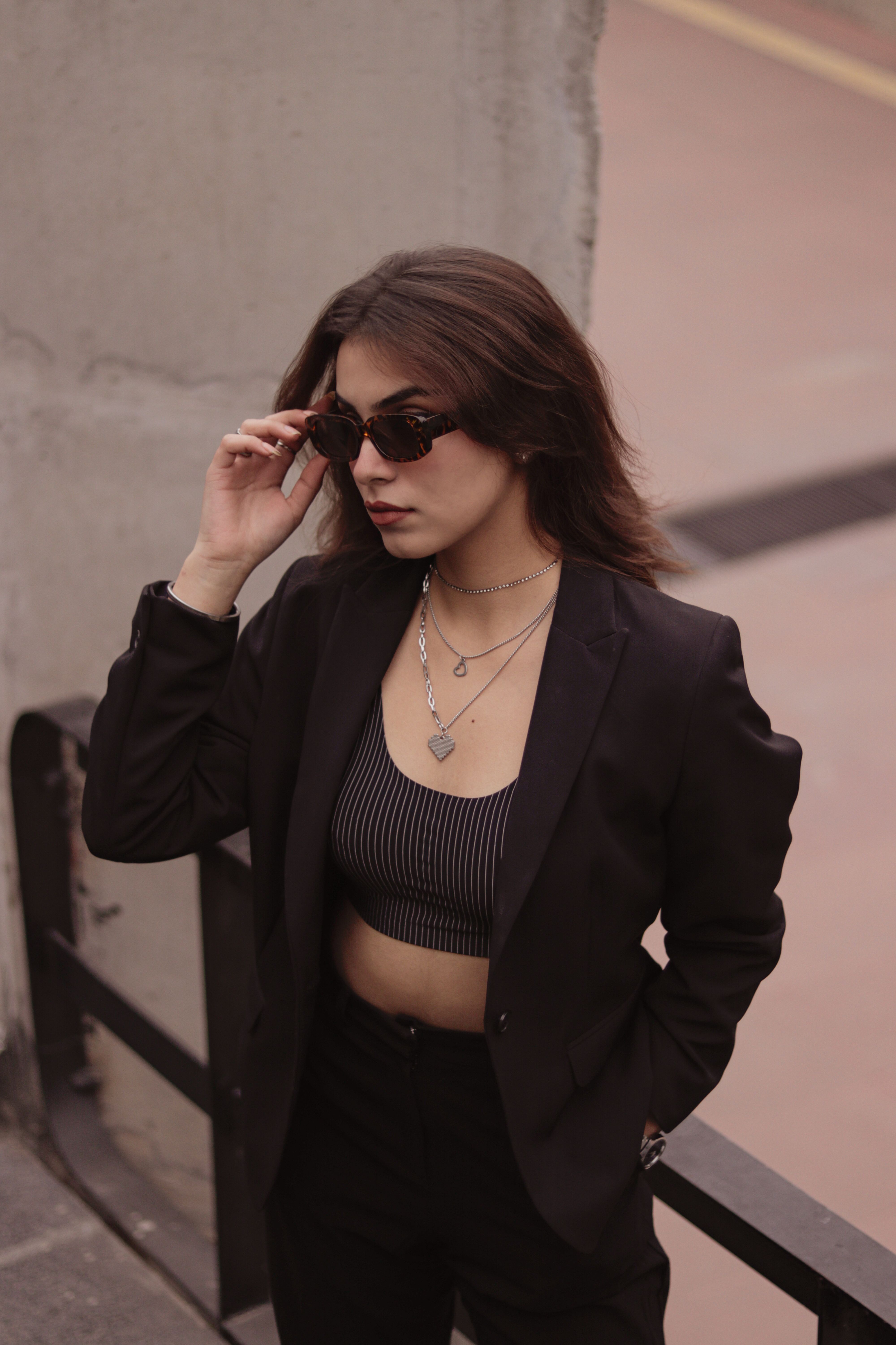 Fashionable woman in sunglasses and blazer, exuding confidence in an urban setting.