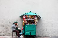 Woman Eating While Seated Next to Mobile Shop Cart