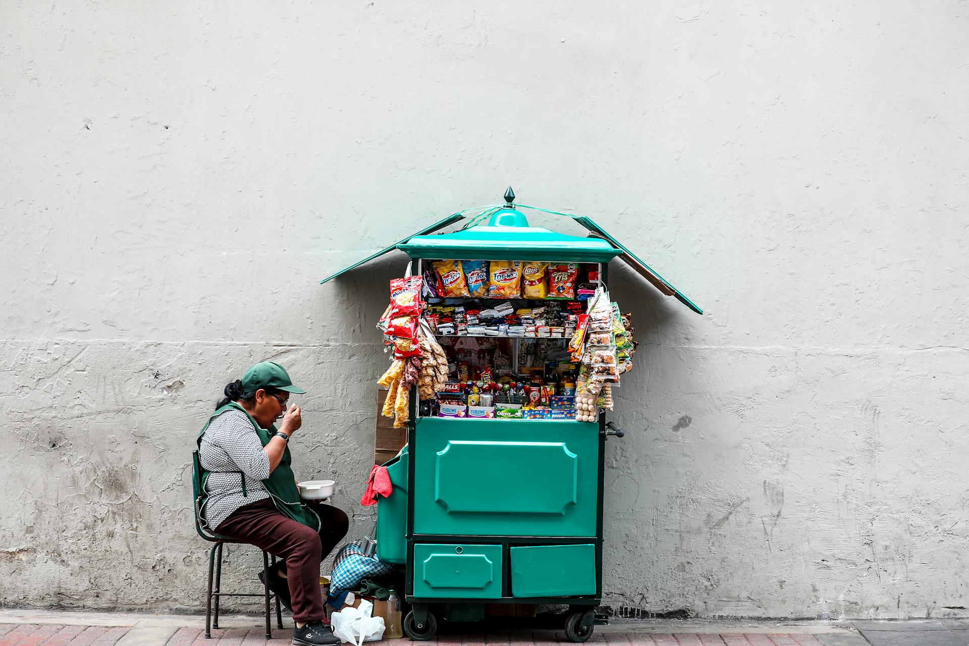 Woman Eating While Seated Next to Mobile Shop Cart