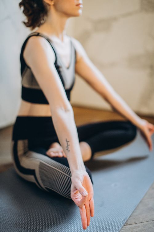 Free A woman sits in lotus pose on a yoga mat, promoting mindfulness and wellness indoors. Stock Photo