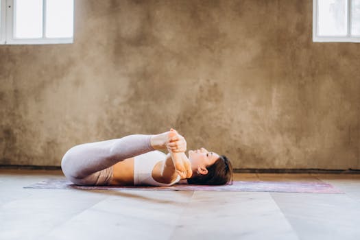 Woman performing a yoga pose on a mat indoors, promoting relaxation and wellness.