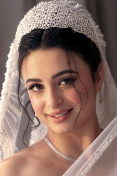 A close-up portrait of a smiling bride in a sparkling veil, exuding elegance and beauty.