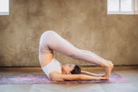 一名女子在室内的瑜伽垫上练习瑜伽，展现了身体的柔韧与内心的专注