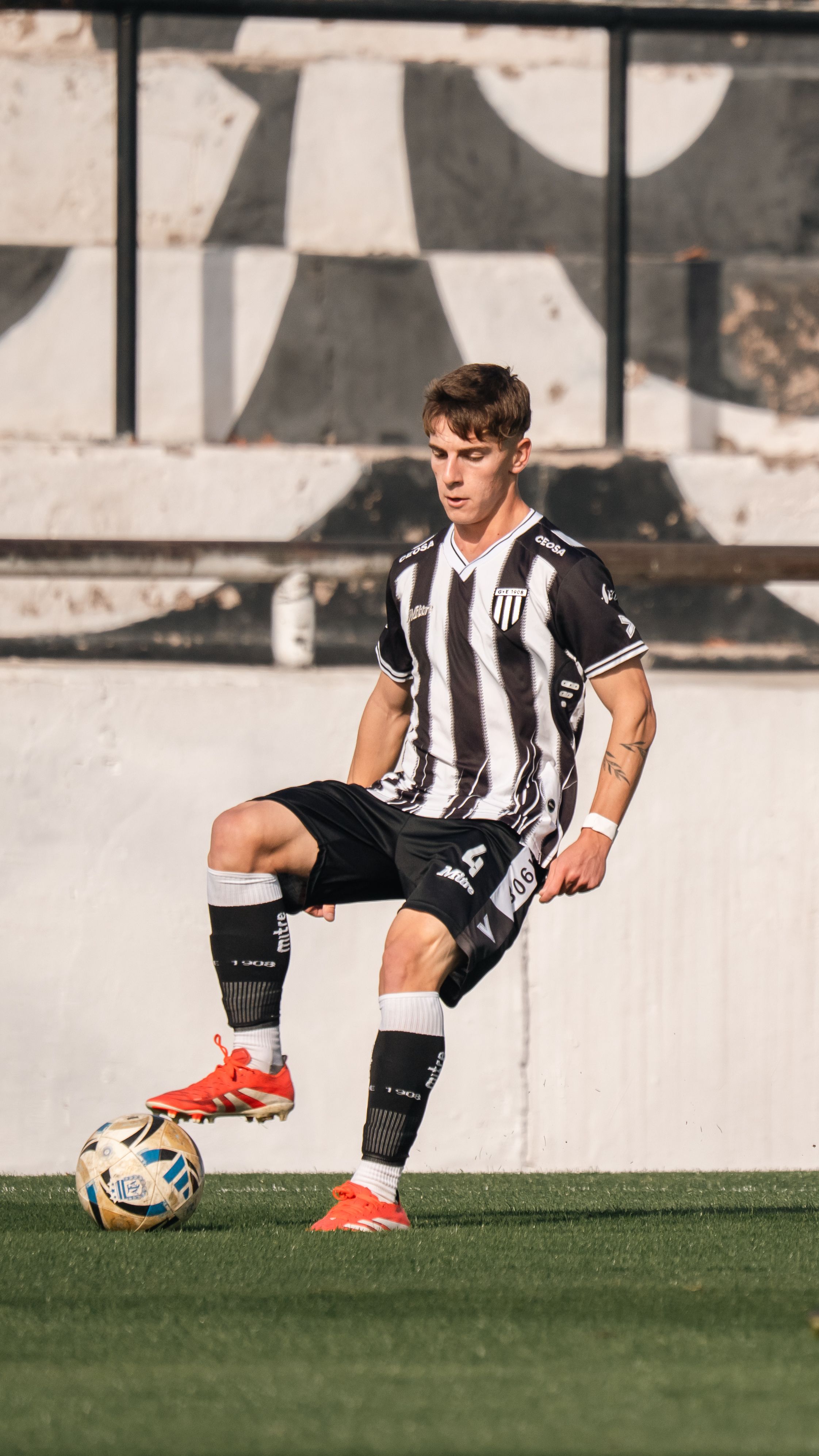 Young soccer player in action on the field, balancing the ball with focus.