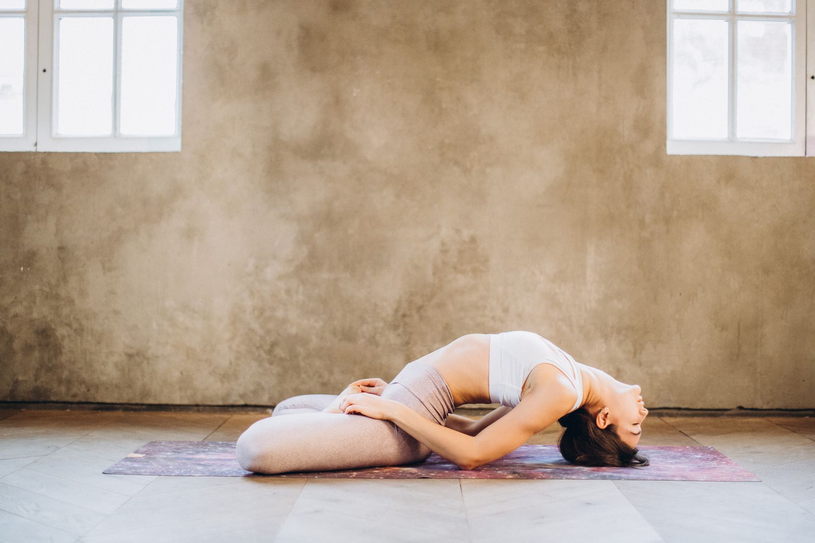 Woman practicing a seated yoga asana pose outdoors on a mat