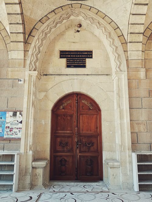 Free Ornate wooden door set in a stone archway at a historic site in Darende, Malatya. Stock Photo