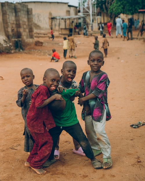 Free Group of Nigerian children playing joyfully in a dirt field, showcasing vibrant culture and community spirit. Stock Photo