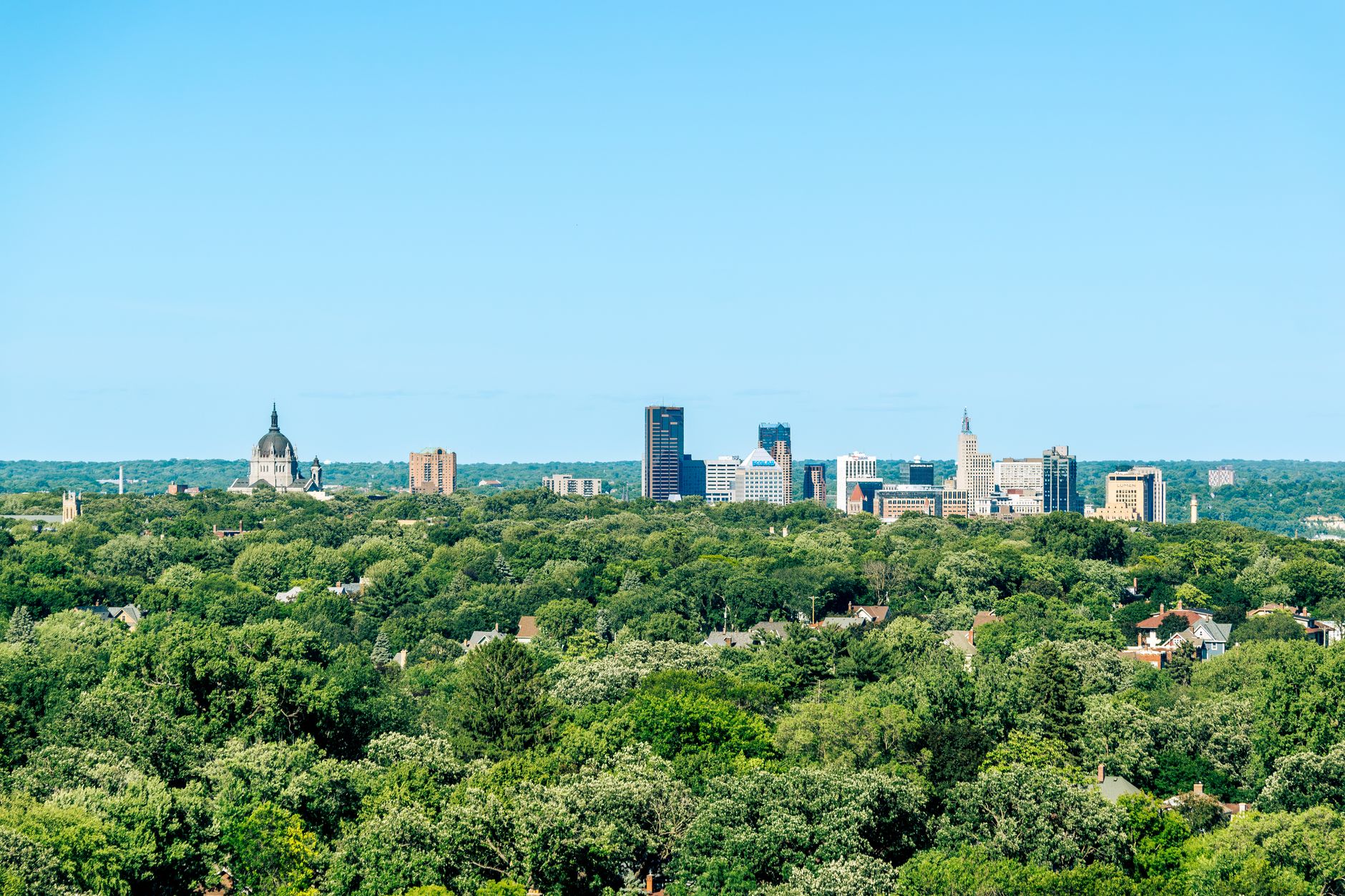 Door hanger delivery in Peoria, IL Door hanger distribution and flyer delivery in Peoria, IL — A panoramic view of Saint Paul's skyline standing behind a vast area of lush greenery under a clear blue sky. above neighborhoods DoorBlitz crews walk