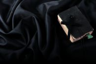 A vintage Bible with a cross resting on elegant black fabric, symbolizing spirituality and faith.