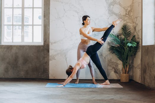 A yoga instructor assists a woman with stretching in a modern studio.