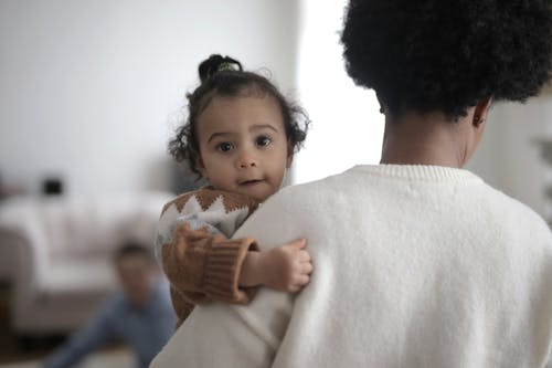 Woman in White Sweater Carrying Baby in Brown Sweater