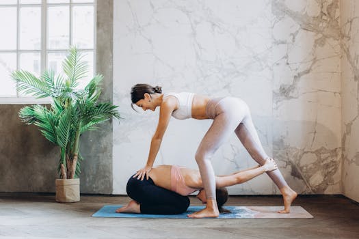 Two women practicing yoga indoors, demonstrating partner yoga poses, promoting fitness and wellbeing.