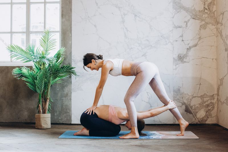 Yoga trainer helping a student with a pose