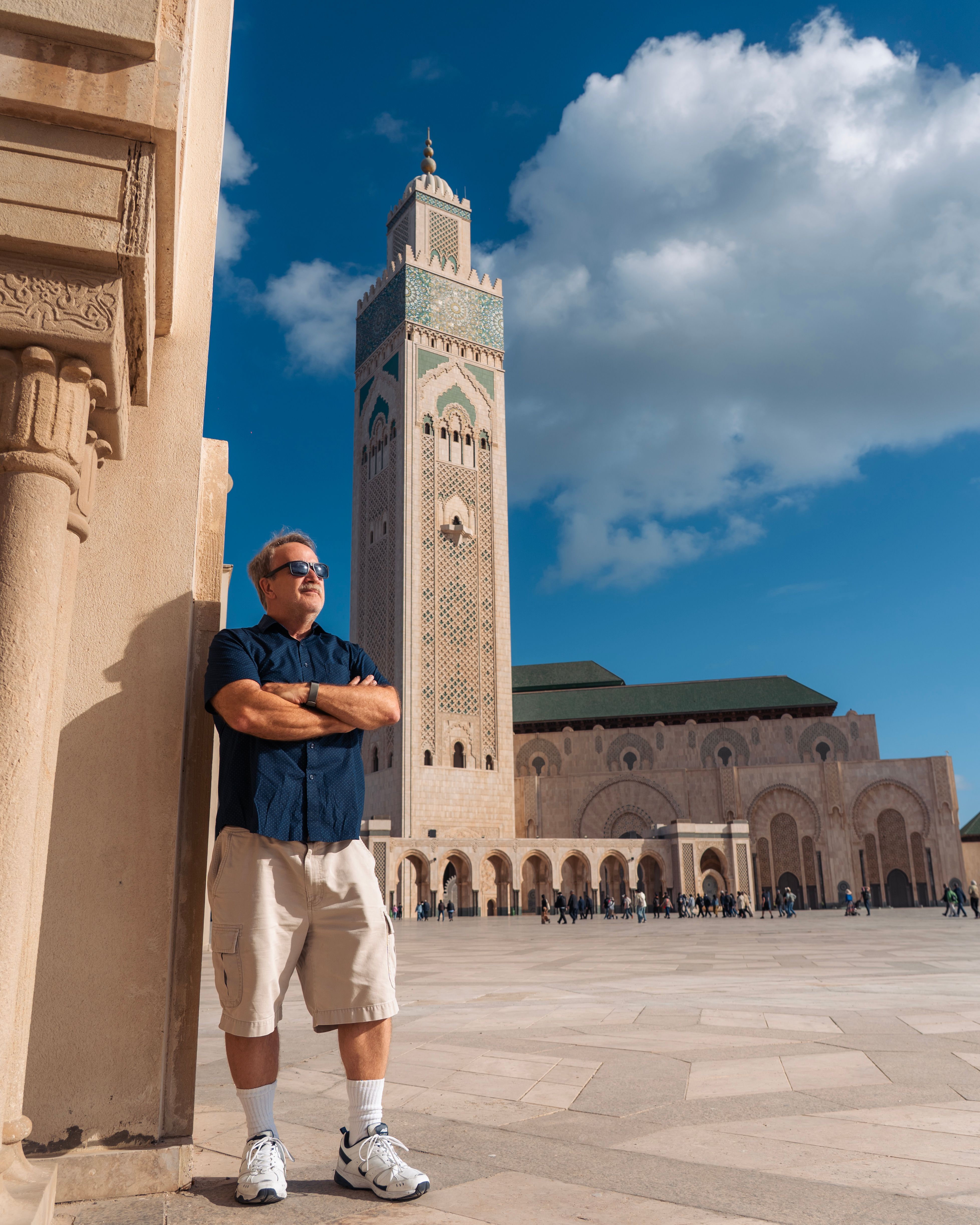 A man stands outside Hassan II Mosque in Casablanca, Morocco with clear blue skies.
