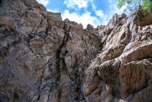 Free Dramatic rocky cliff rising under a bright blue sky, showcasing nature's rugged beauty. Stock Photo