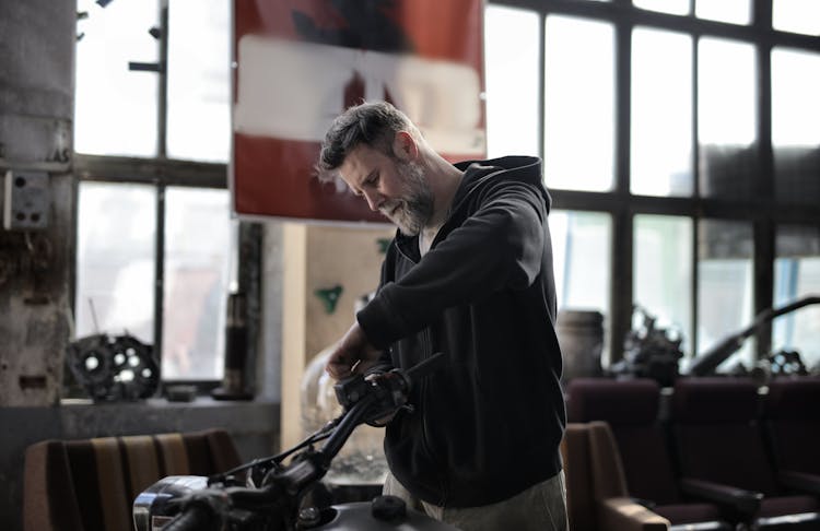 Mature Man Fixing Motorcycle Handlebar In Garage