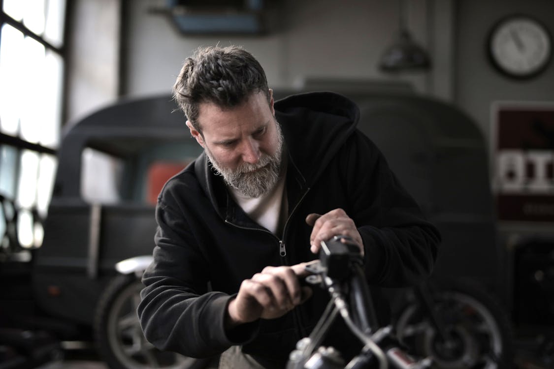 бесплатная Жестокий мужчина ремонтирует мотоцикл в мастерской Стоковое фото