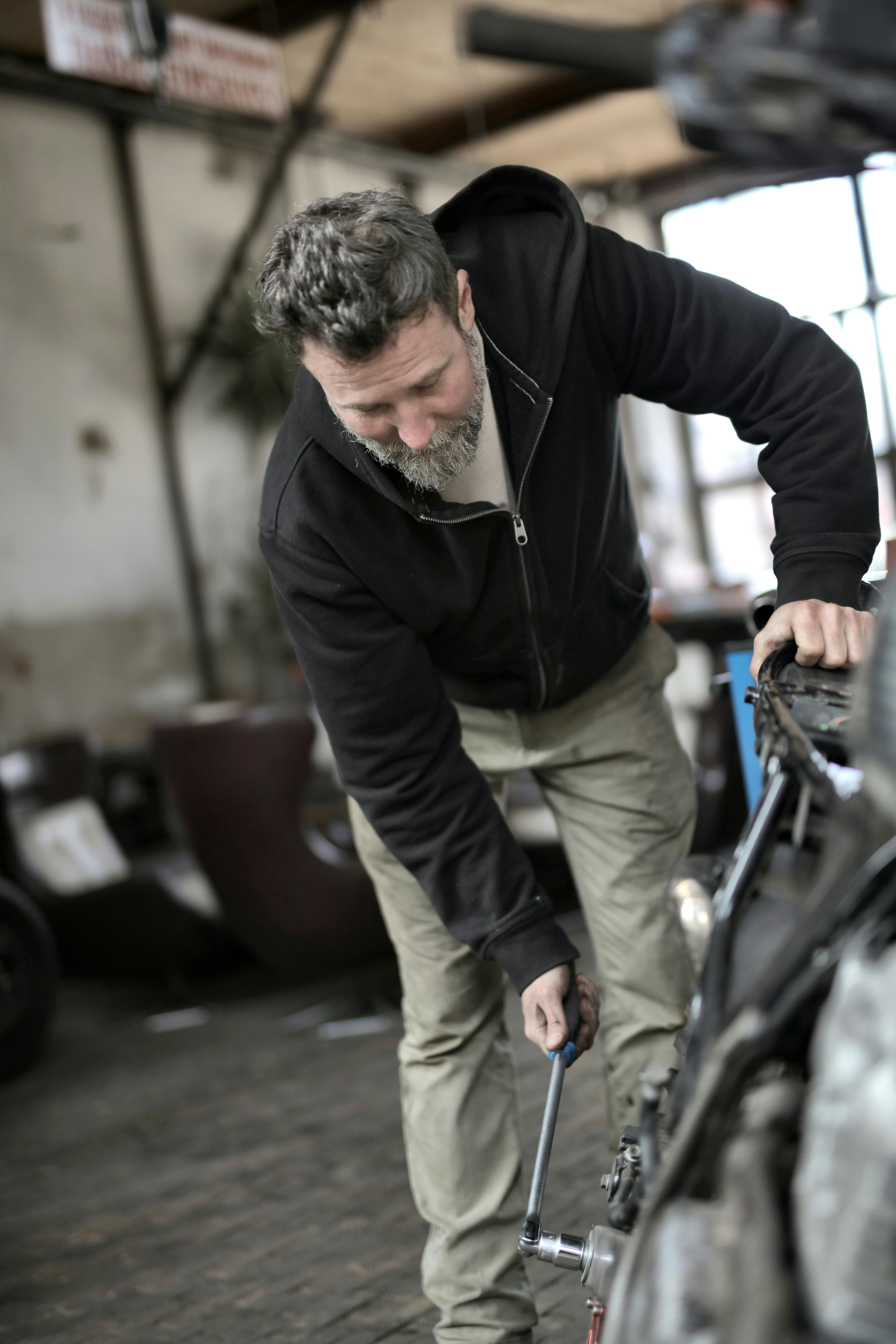 busy male mechanic fixing vehicle in garage