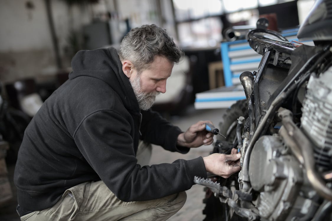 Free Bearded man fixing motorcycle in workshop Stock Photo