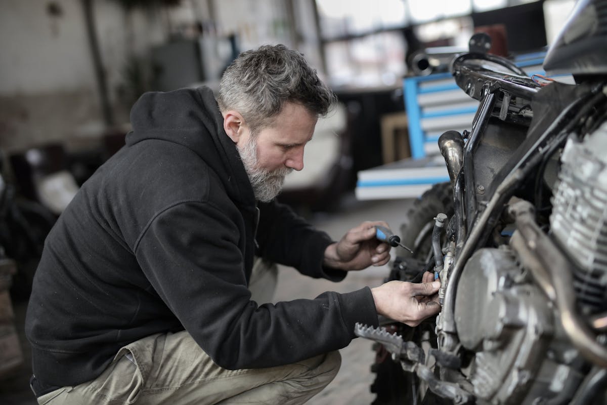 Bearded man fixing motorcycle in workshop
