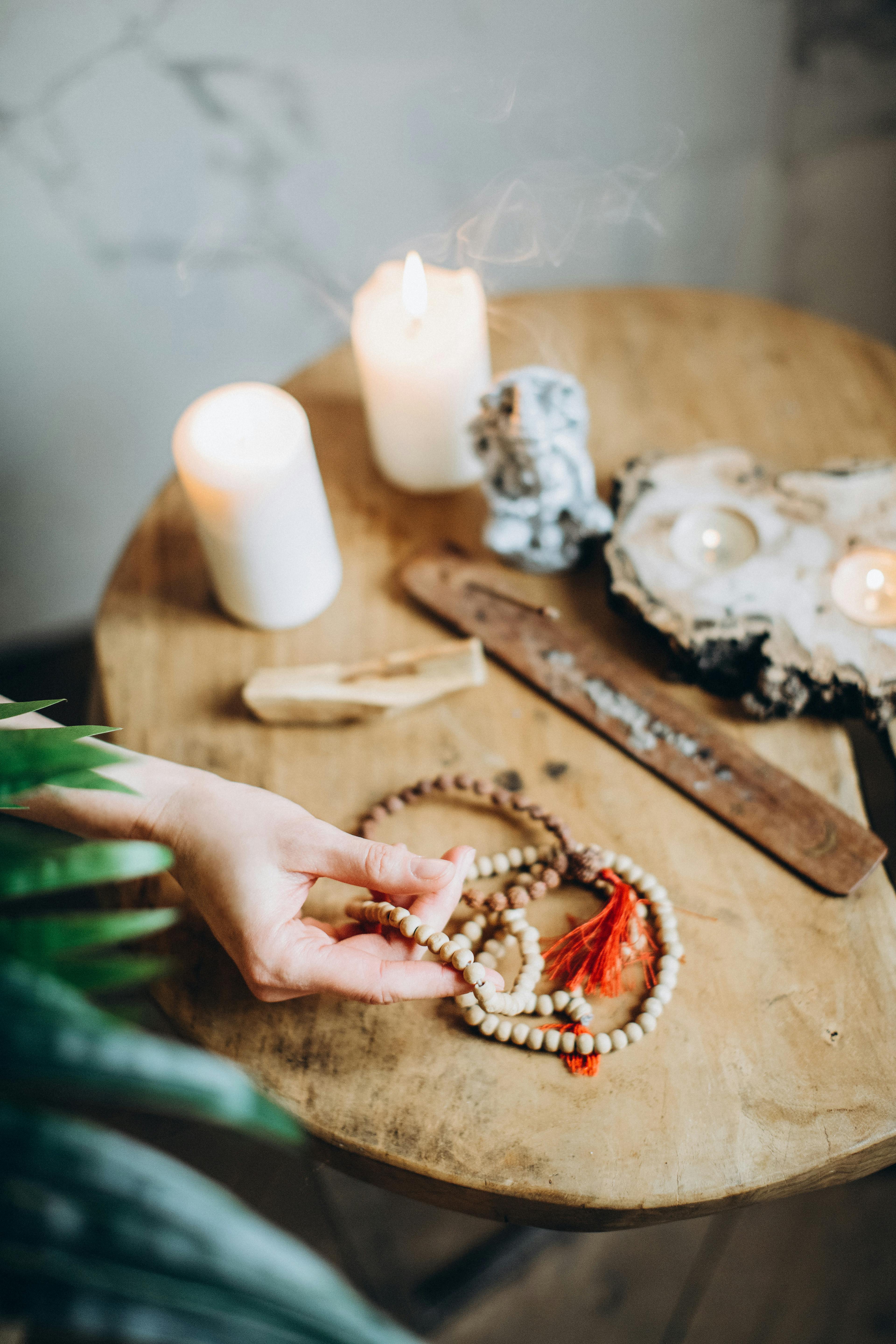 Free Cozy meditation space featuring candles, prayer beads, and incense on a wooden table. Stock Photo