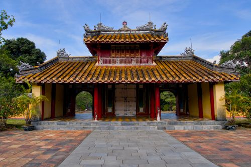 Free A beautiful Vietnamese temple featuring an ornate tiled roof and traditional architectural details set in a lush garden. Stock Photo