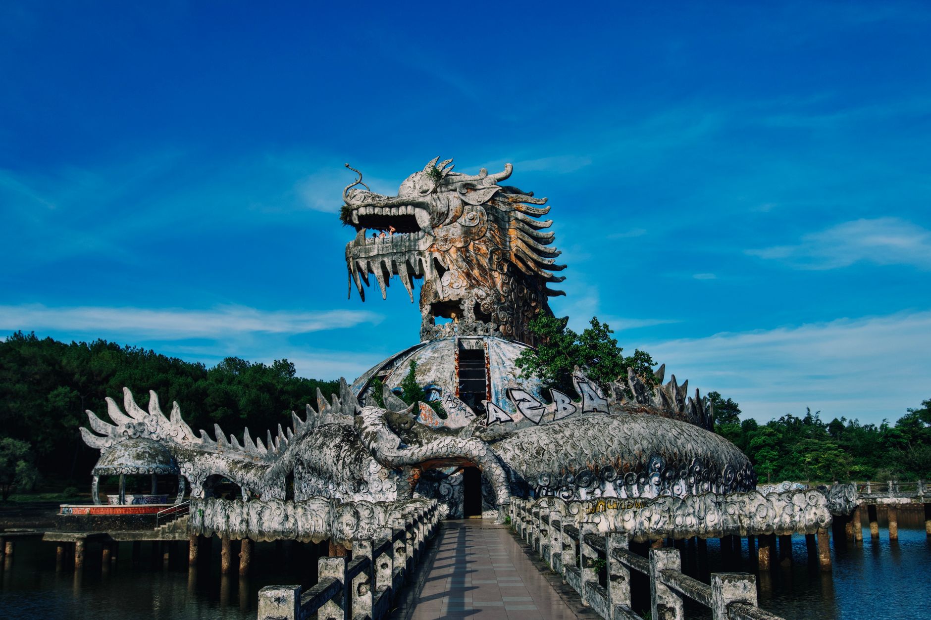 An abandoned dragon-themed structure in Vietnam's Ho Thuy Tien Waterpark under clear blue sky.