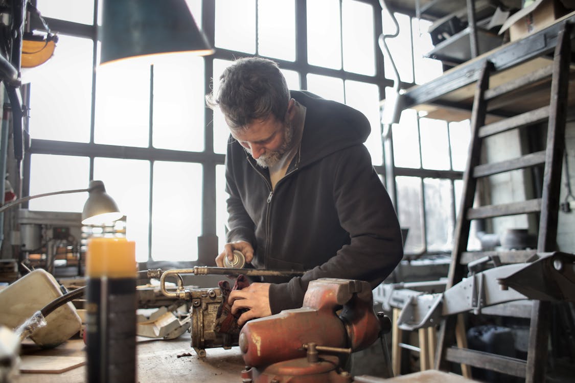 Focused male mechanic using spray paint on metal detail