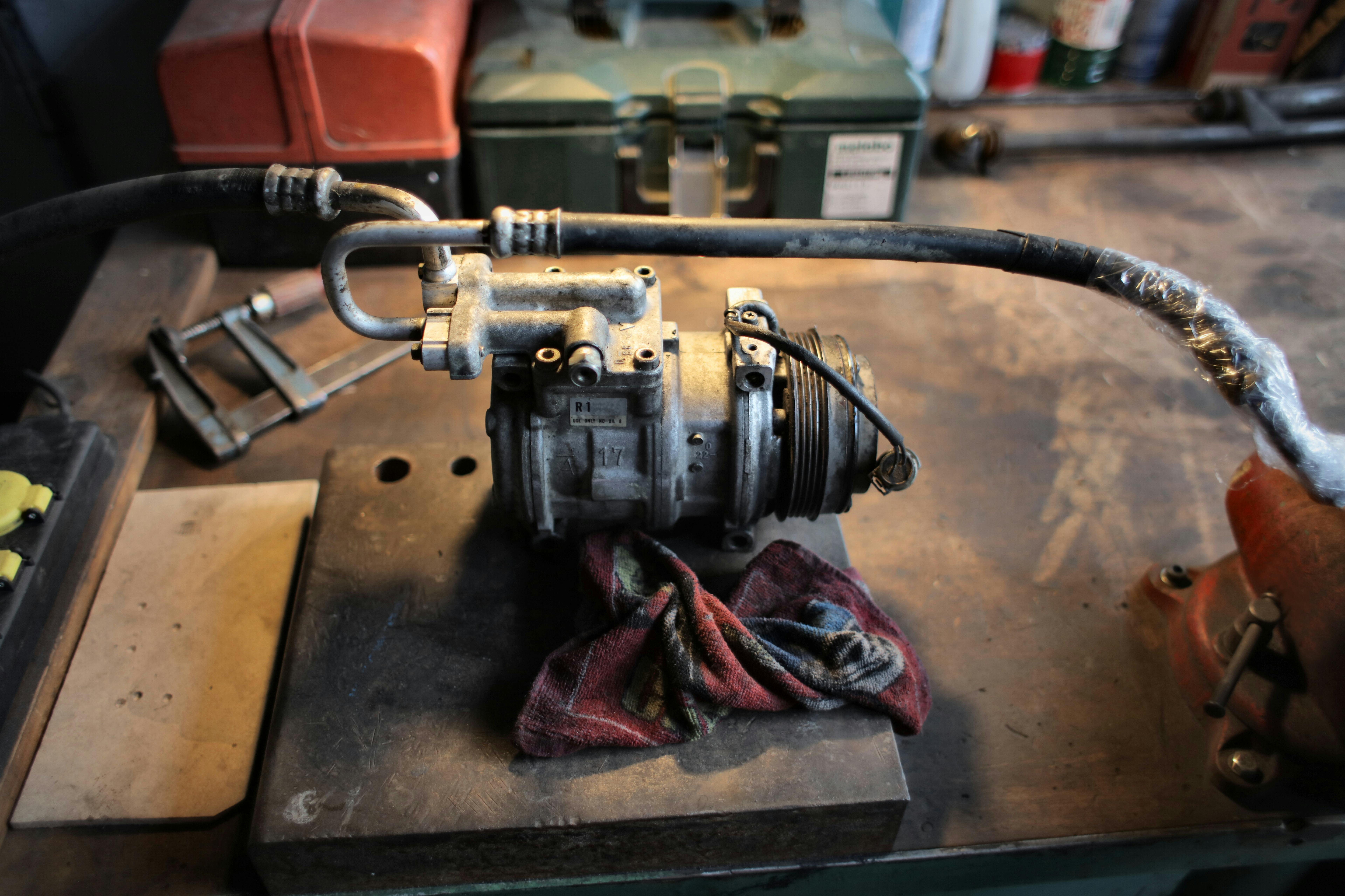 metal air conditioning compressor on workbench in garage