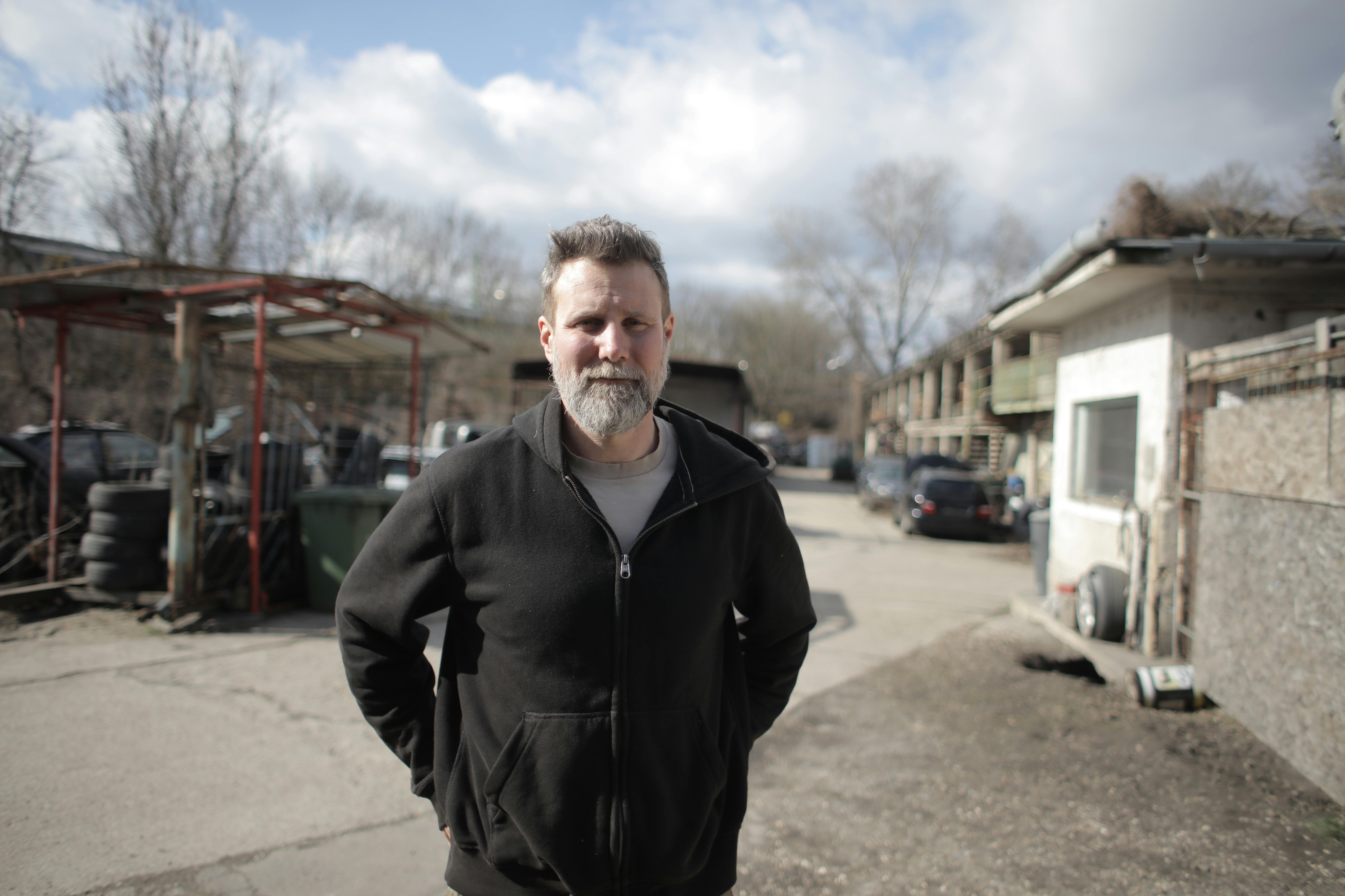 smiling male mechanic standing near garage