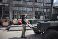 Side view of brutal male mechanic in casual outfit closing car trunk while standing on background of shabby building
