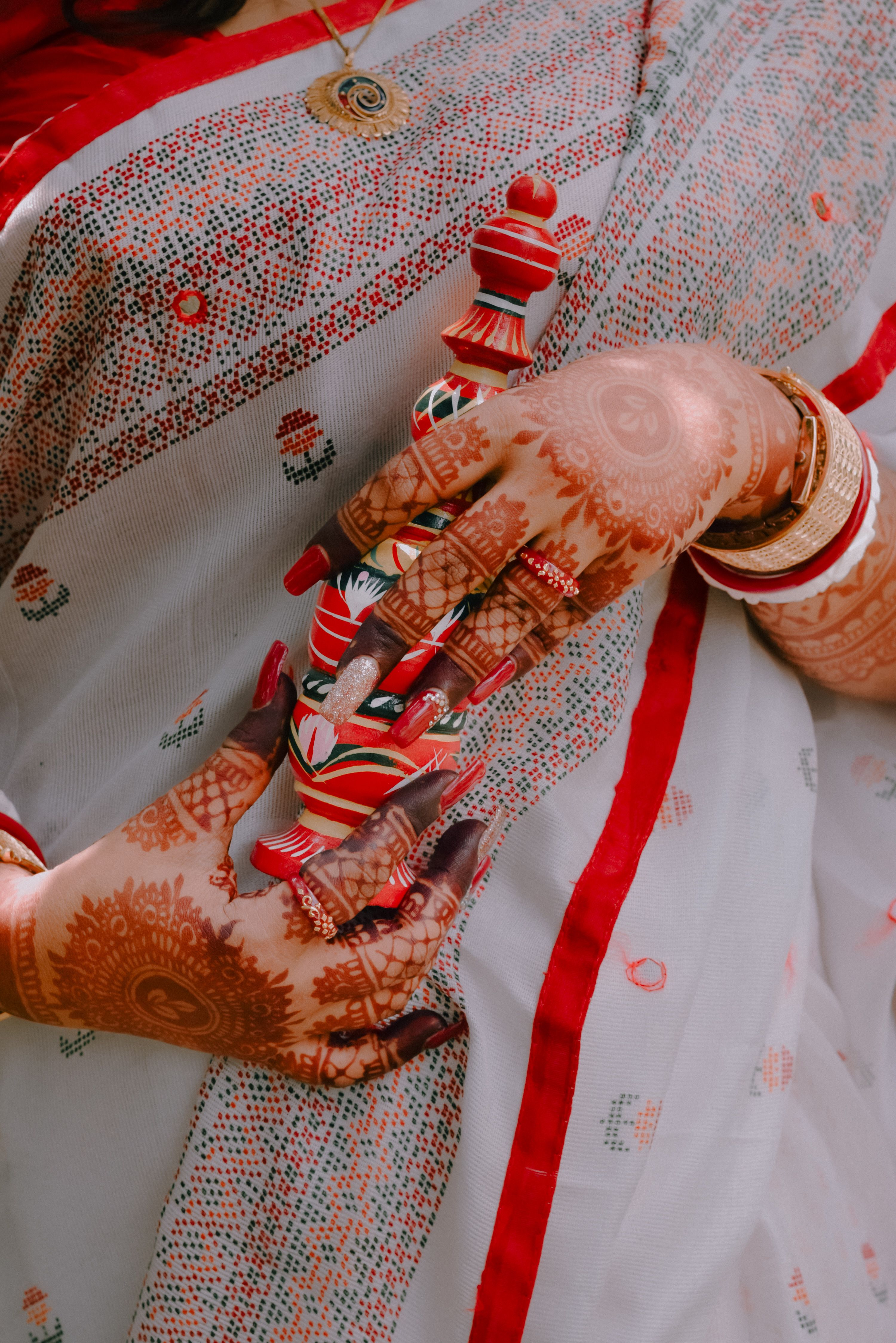 Intricate henna designs on Indian bride's hands with traditional bangles in Howrah, India.
