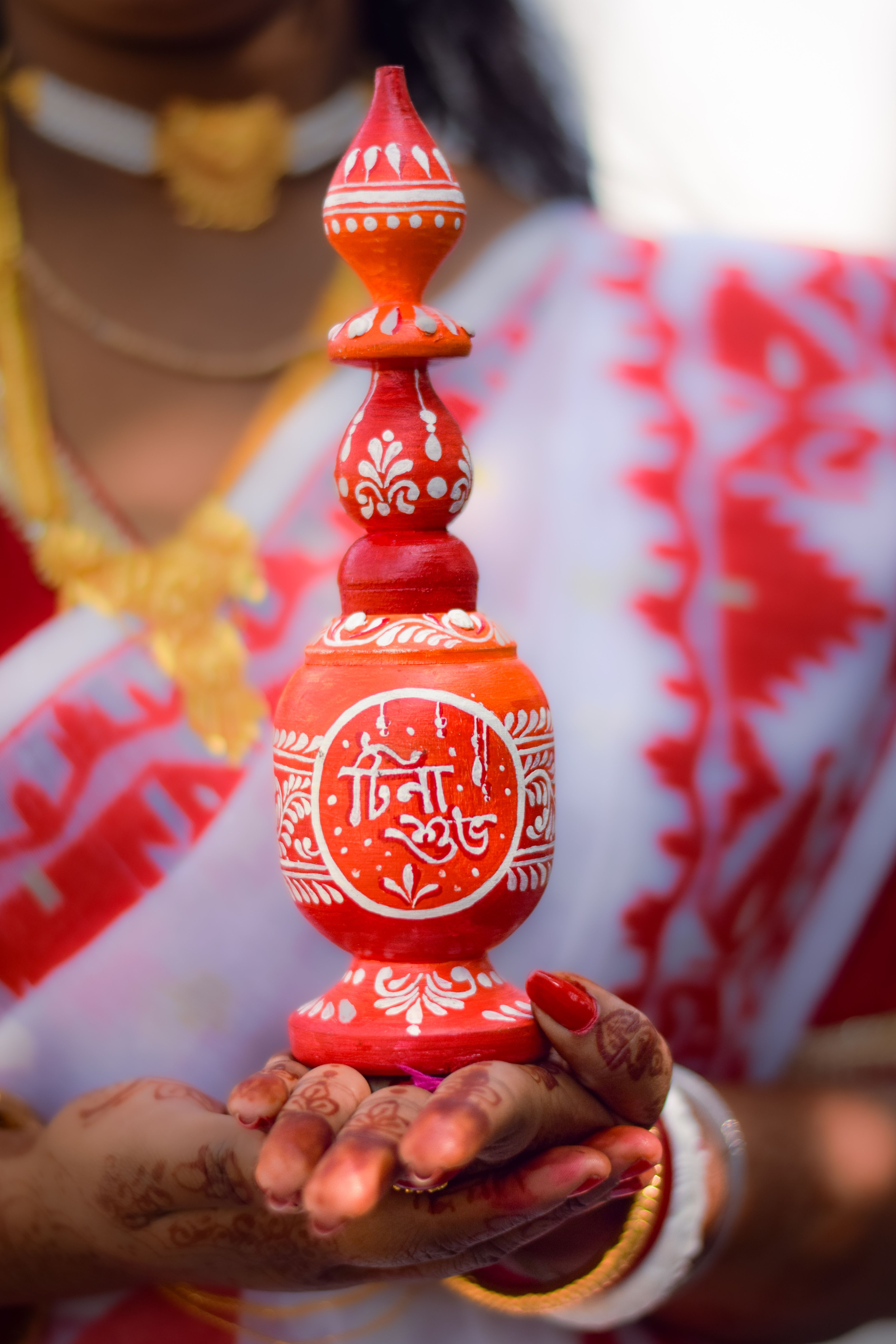 A close-up of a traditional Bengali sindoor pot used in marriage rituals, held by a woman in Howrah, India.