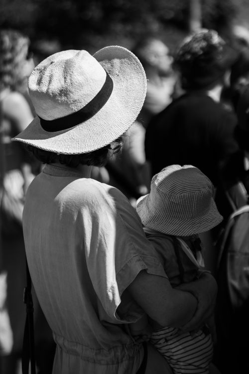 Free A candid black and white portrait of a parent holding a child in a crowd during a sunny day in Dublin. Stock Photo